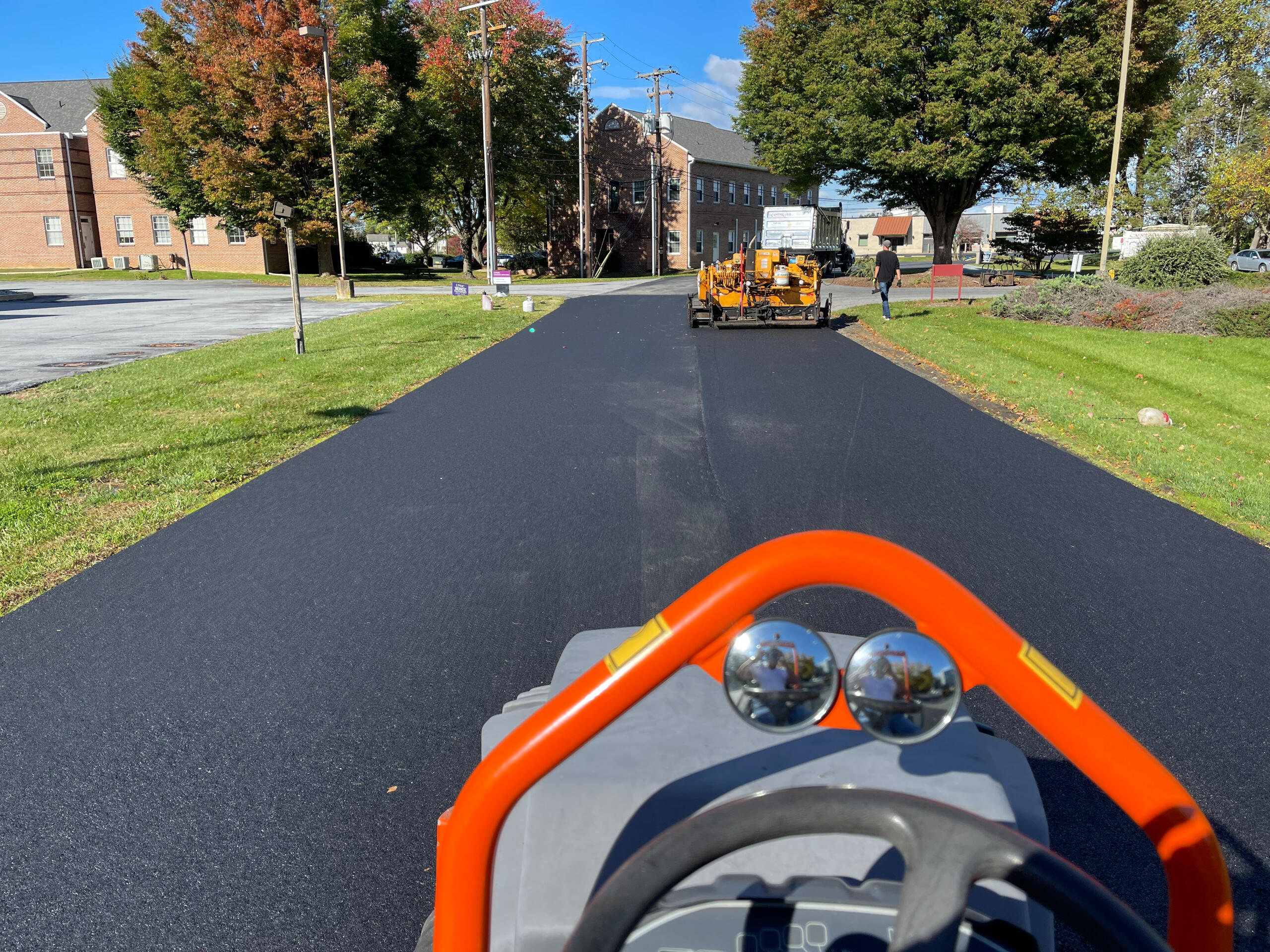 Paver laying fresh hot-mix asphalt down a residential street