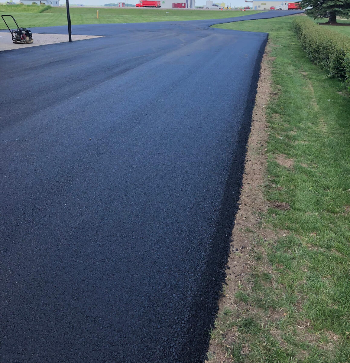 Fresh black asphalt edge against green grass
